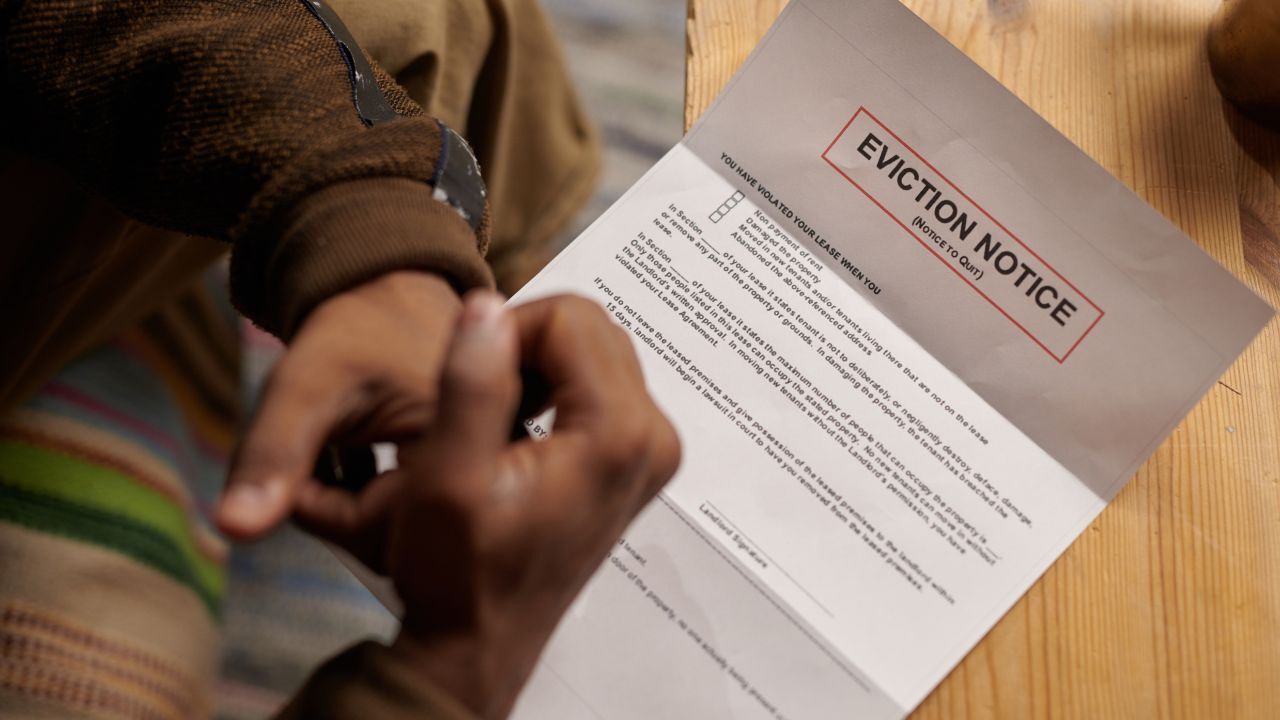 Person holding an eviction notice document with hands folded over it.