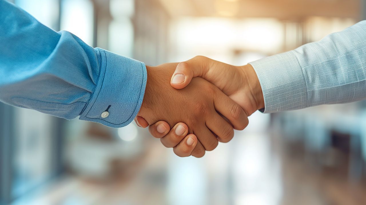 Two people shaking hands in a professional setting, symbolizing agreement or partnership.