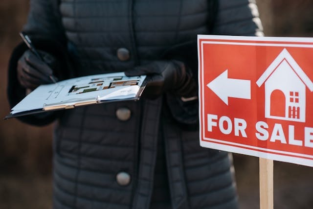 person standing behind a for sale sign